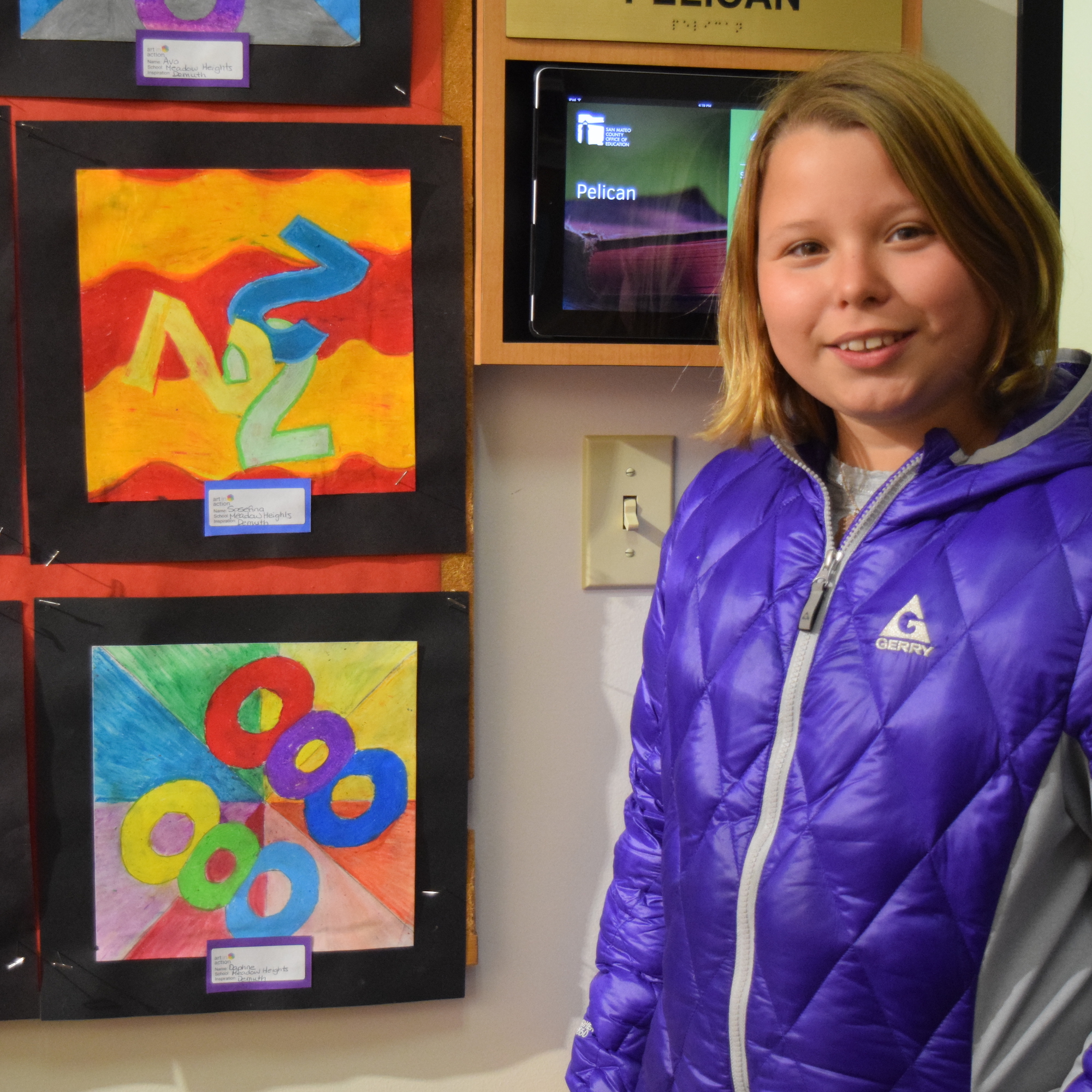 A student stands by her artwork displayed at the San Mateo County Office of Education.